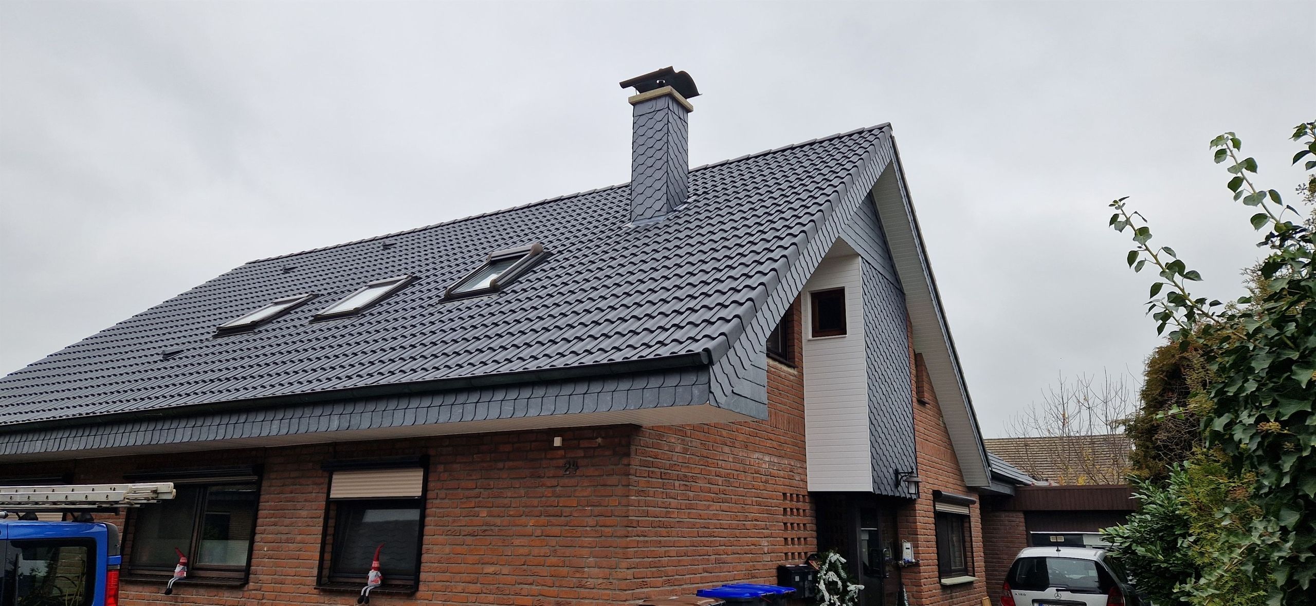 Neu eingedecktes Dach mit Schieferverkleidung, Schornstein und Dachfenstern